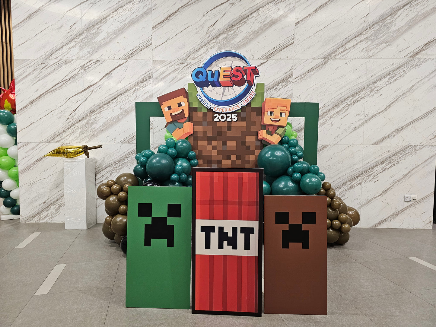 Decorative stand with Minecraft-themed elements and 'Quest 2025' branding.