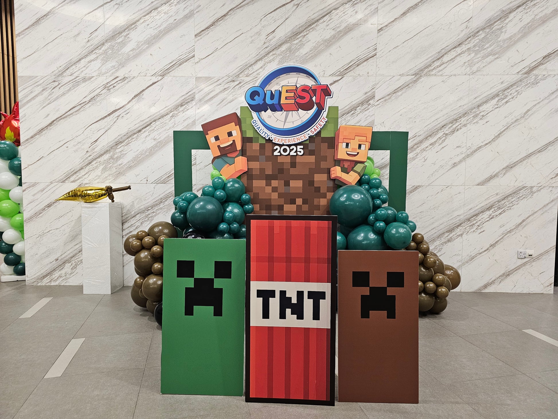 Decorative stand with Minecraft-themed elements and 'Quest 2025' branding.