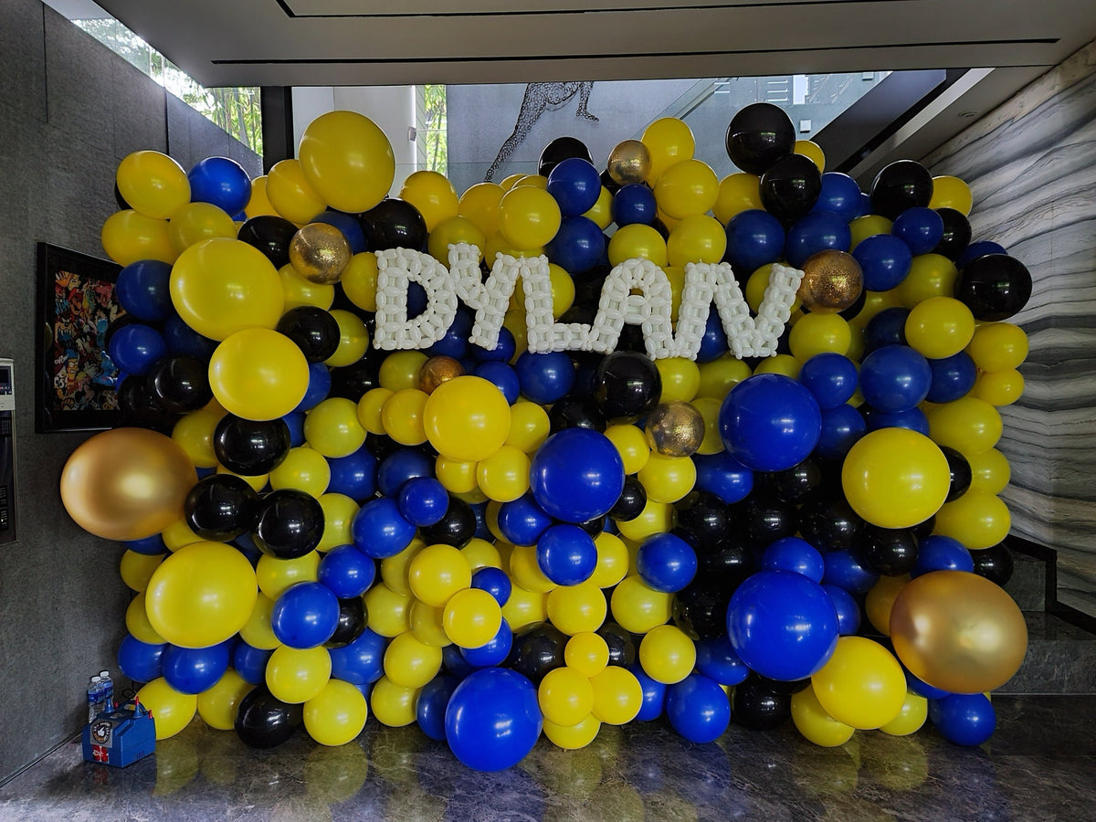 Organic full balloon wall in yellow, blue and black with twisted balloon name